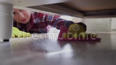 女人用专用清洁剂清洁床下的地板。